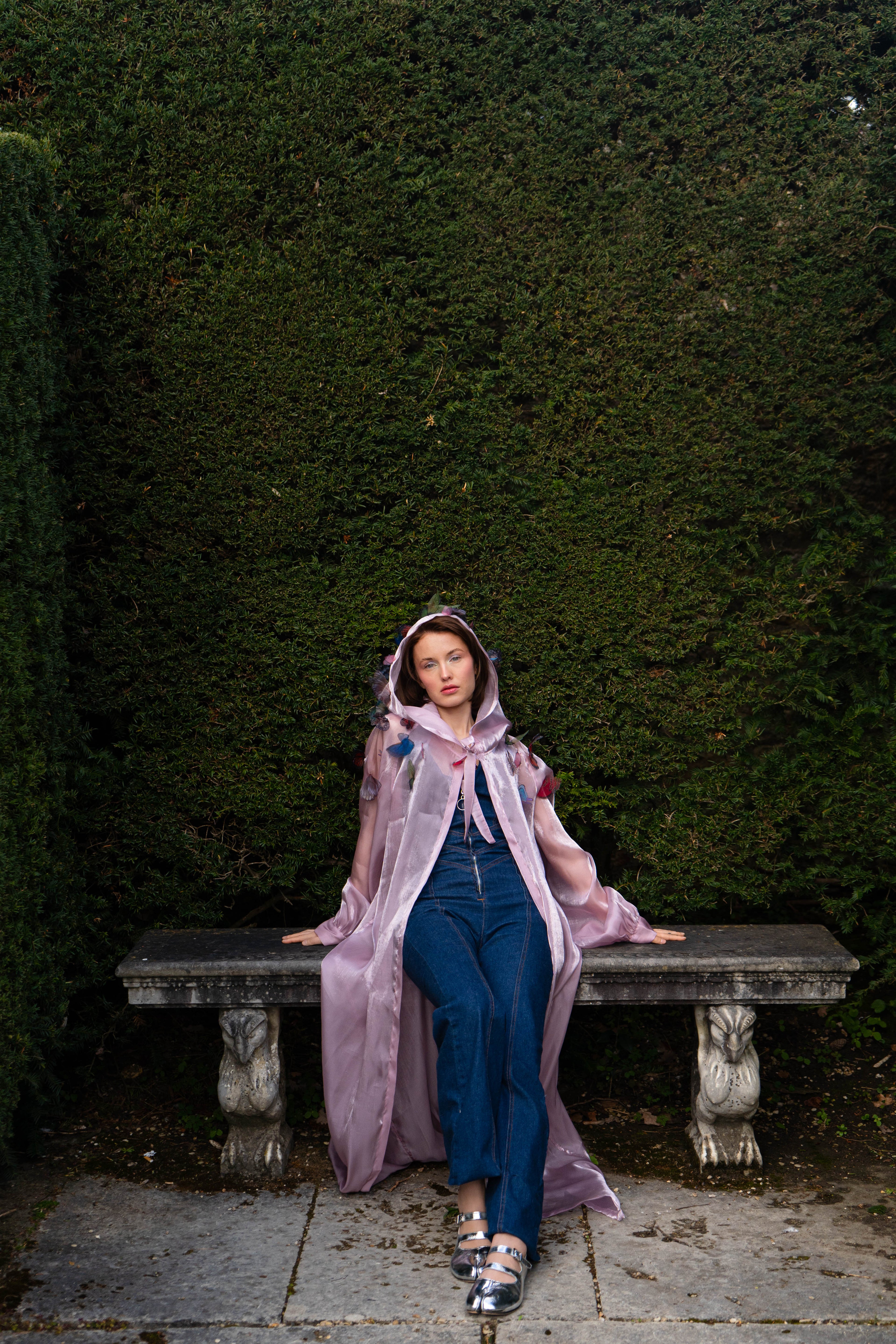 LA CAPE ÉTHÉRÉE — ROSE AUBE

Silhouette vaporeuse &amp; reflets lunaires.

Voile iridescent de haute légèreté captant la lumière pour un effet holographique aux nuances rosées et nacrées.

Papillons découpés et cousus main individuellement, créant un relief organique et poétique sur l'ensemble de la pièce.

Chaque modèle est une pièce unique : le positionnement des papillons étant réalisé à la main, chaque cape possède sa propre constellation de motifs.
