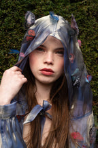 LA CAPE ÉTHÉRÉE — BLEU MIROIR

Silhouette vaporeuse &amp; reflets lunaires.

Voile iridescent de haute légèreté captant la lumière pour un effet holographique unique.

Papillons découpés et cousus main individuellement, créant un relief organique et poétique sur l'ensemble de la pièce.

Chaque modèle est une pièce unique : le positionnement des papillons étant réalisé à la main, chaque cape possède sa propre constellation de motifs.

Volume aérien avec capuche délicate pour une allure de conte de fées.