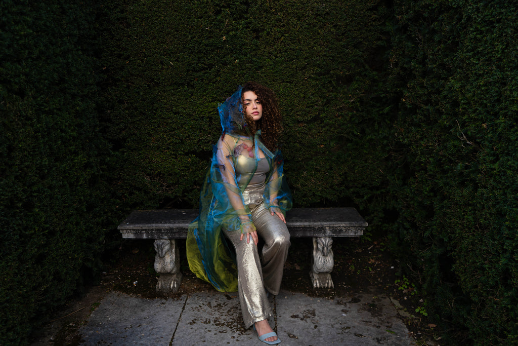 LA CAPE ÉTHÉRÉE — VERT BOREAL

Silhouette vaporeuse &amp; éclats magnétiques.

Voile iridescent de haute légèreté captant la lumière pour un effet holographique aux reflets vert d'eau et dorés.

Papillons découpés et cousus main individuellement, créant un relief organique et poétique sur l'ensemble de la pièce.

Chaque modèle est une pièce unique : le positionnement des papillons étant réalisé à la main, chaque cape possède sa propre constellation de motifs.