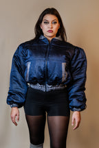 Doudoune réversible - Bleu & argent pailletés. Face bleue matelassée. Face argentée avec finition pailletée. Rembourrée, chaude et confortable. THERMO 150. Manches bouffantes. Fermeture zippée. Poches latérales. Edition limitée à 3 exemplaires.