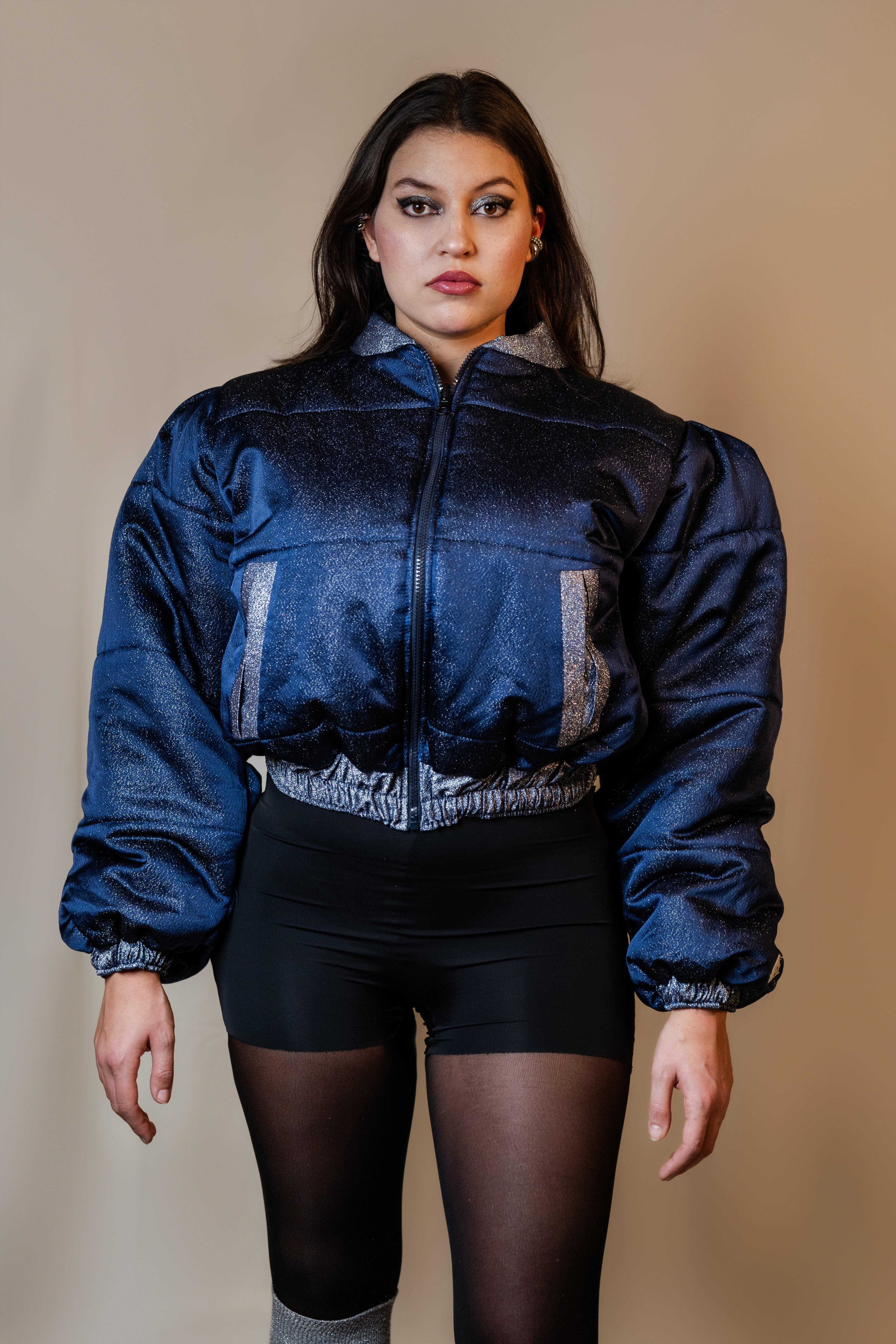 Doudoune réversible - Bleu & argent pailletés. Face bleue matelassée. Face argentée avec finition pailletée. Rembourrée, chaude et confortable. THERMO 150. Manches bouffantes. Fermeture zippée. Poches latérales. Edition limitée à 3 exemplaires.