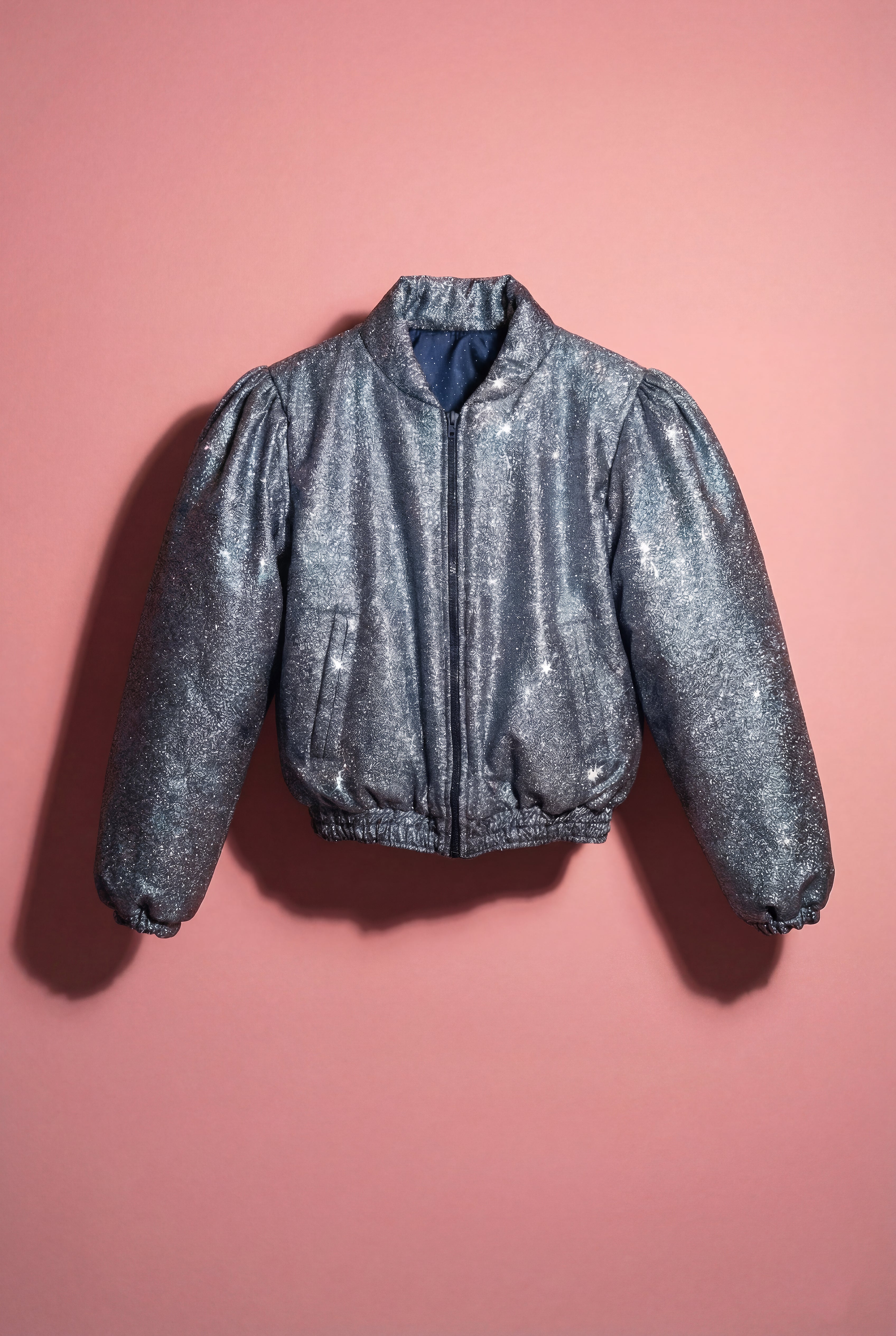 Doudoune réversible - Bleu & argent pailletés. Face bleue matelassée. Face argentée avec finition pailletée. Rembourrée, chaude et confortable. THERMO 150. Manches bouffantes. Fermeture zippée. Poches latérales. Edition limitée à 3 exemplaires.