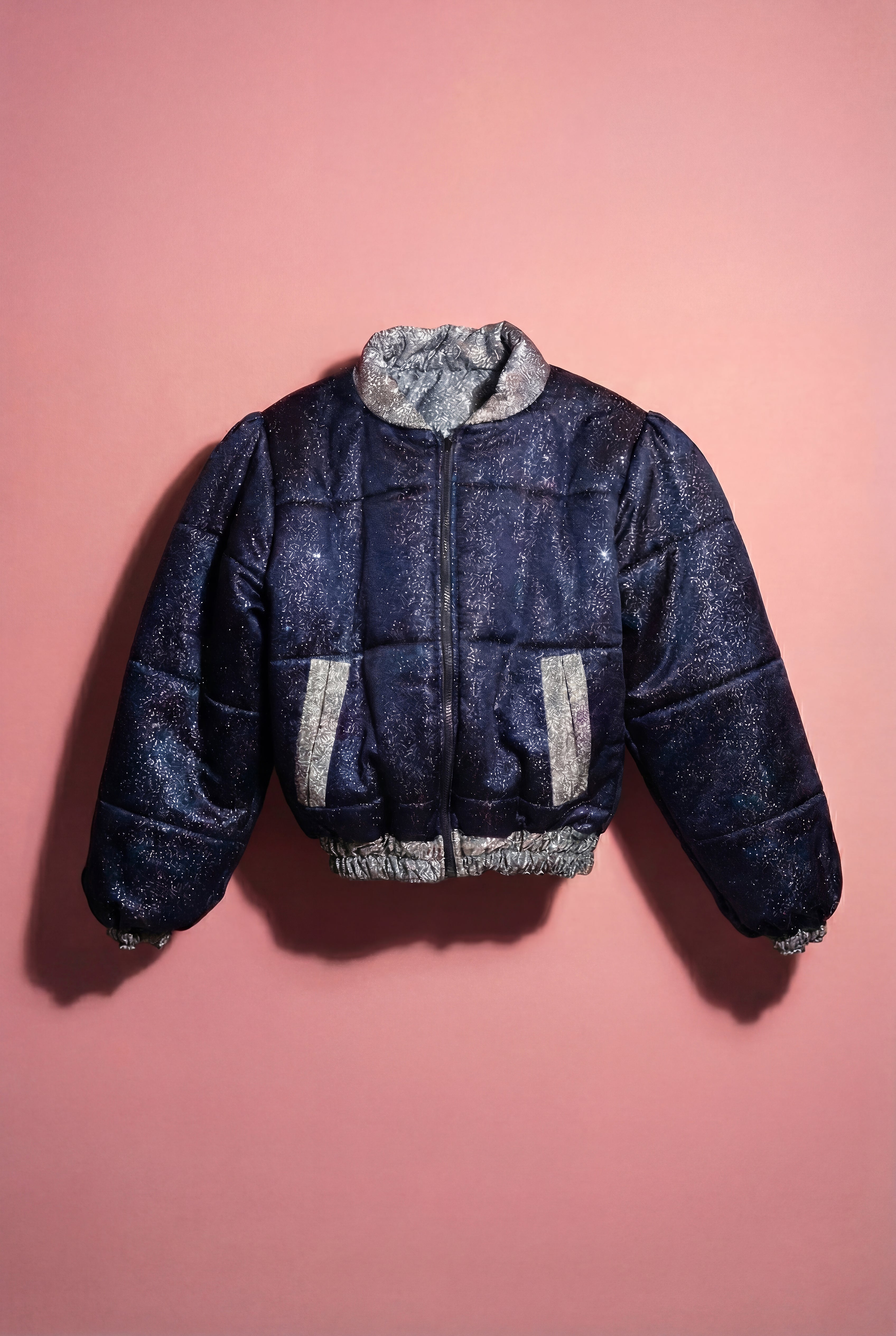Doudoune réversible - Bleu & argent pailletés. Face bleue matelassée. Face argentée avec finition pailletée. Rembourrée, chaude et confortable. THERMO 150. Manches bouffantes. Fermeture zippée. Poches latérales. Edition limitée à 3 exemplaires.