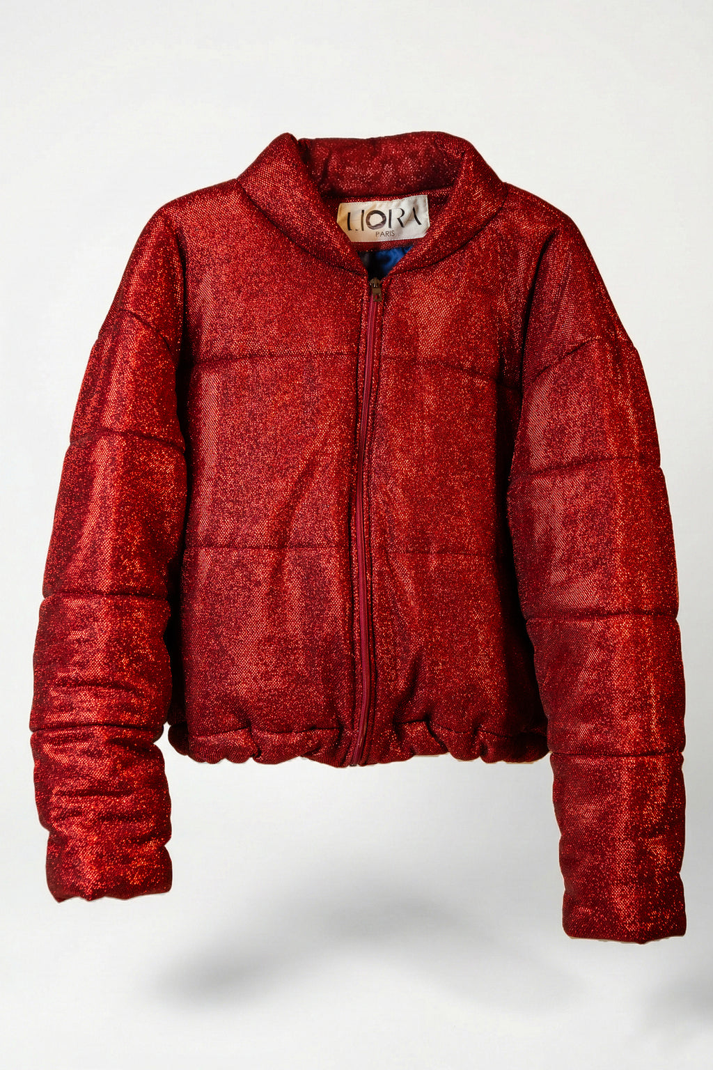 Doudoune - Rouge profond pailletée. Oversize, matelassée et rembourrée. Doublure en satin bleu. THERMO 180. Fermeture zippée et poches latérales zippées. Edition limitée à 3 exemplaires