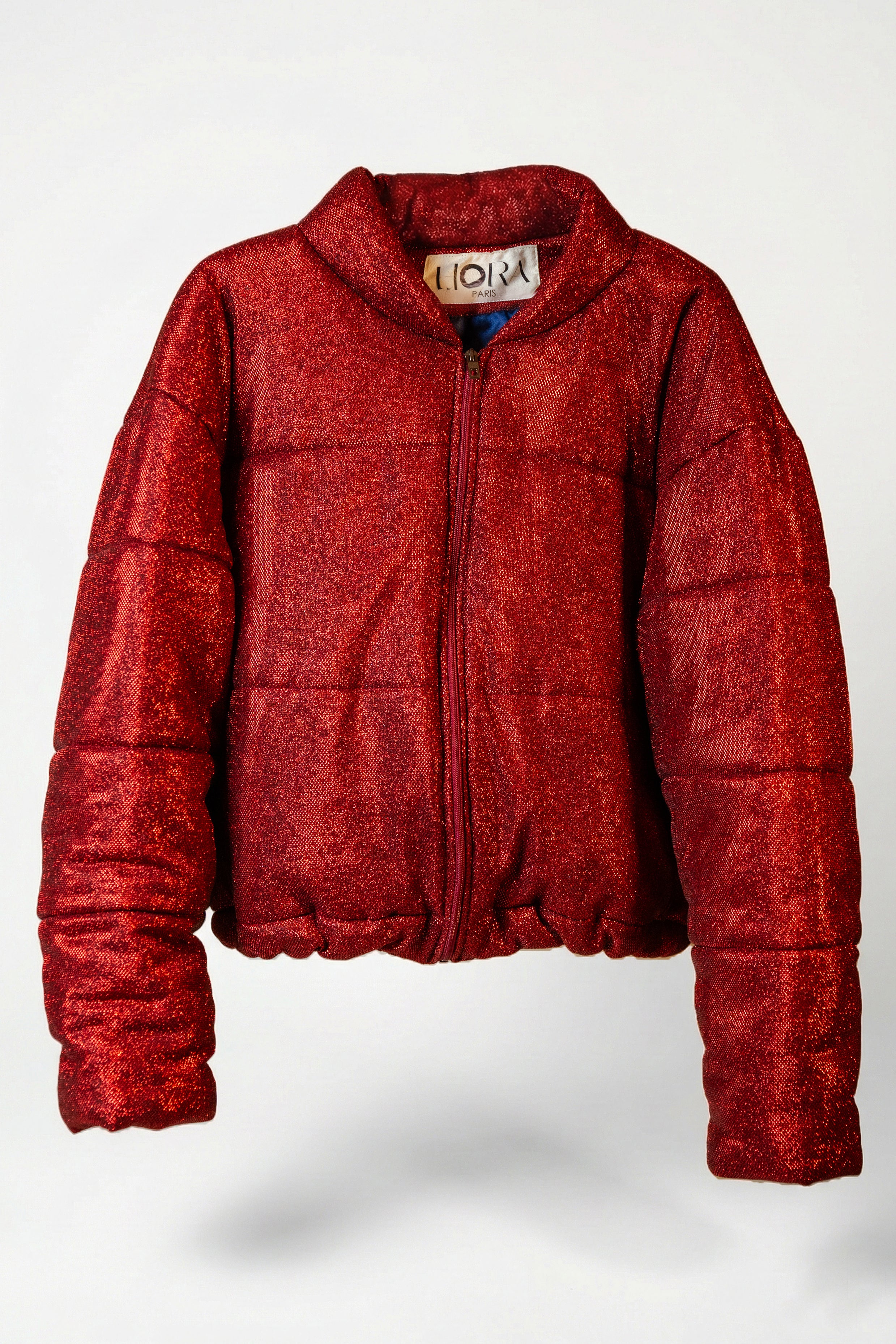 Doudoune - Rouge profond pailletée. Oversize, matelassée et rembourrée. Doublure en satin bleu. THERMO 180. Fermeture zippée et poches latérales zippées. Edition limitée à 3 exemplaires