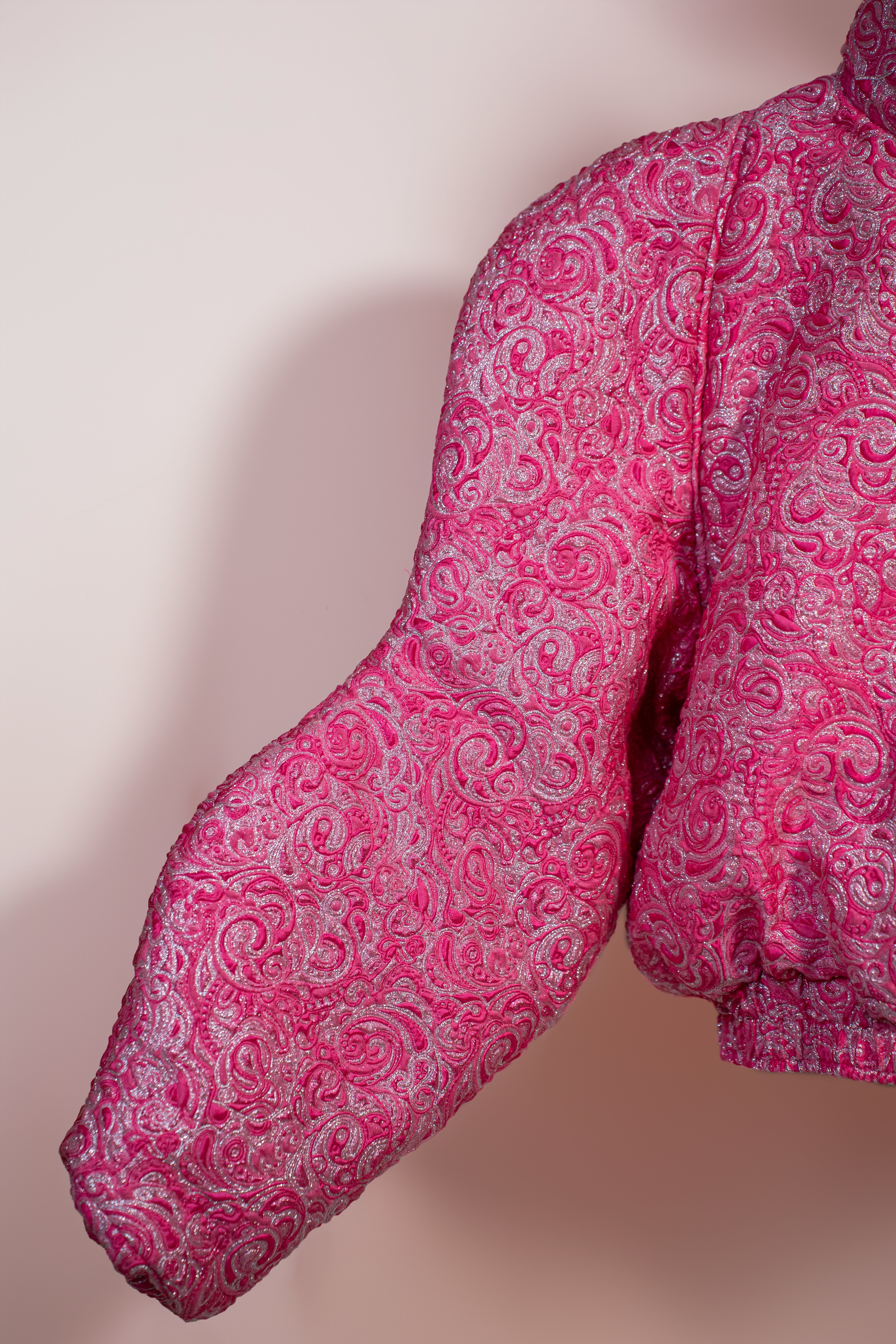 Doudoune rose texturée à effet serti argenté. Manches butterfly structurées. Rembourrage THERMO 180. Doublure satinée grise. Fermeture zippée, poches latérales. Edition limitée à 3 exemplaires